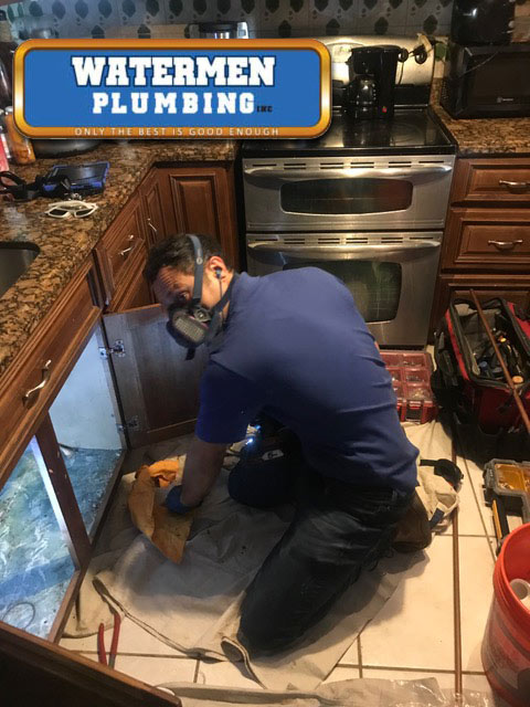 Hallandale Beach drain cleaning expert on the kitchen floor surrounded by tools